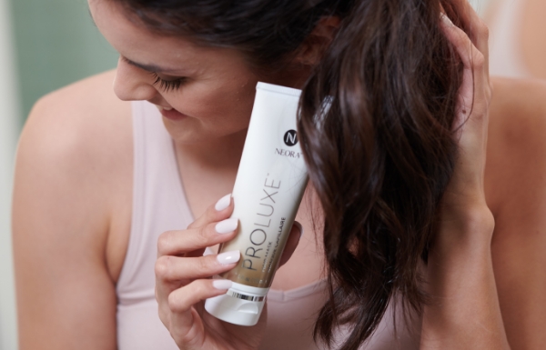 Image of woman holding a tube of ProLuxe Hair Mask at her hair.